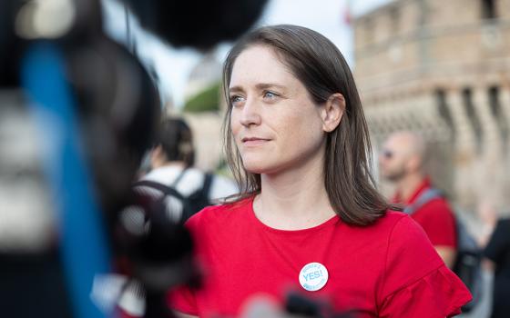Kate McElwee, executive director of the Women’s Ordination Conference, speaks to a reporter during a "Don't Kick the Can, Women Can Be Priests” action in Rome during the Synod on Synodality meeting in October. The group is now planning a women’s strike during Lent of 2025. (Courtesy of Women's Ordination Conference)