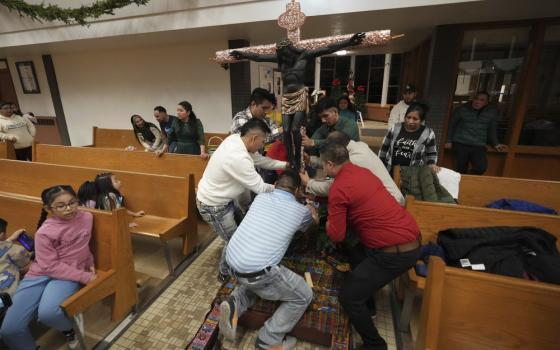 People in church surround large crucifix arranging it into place.