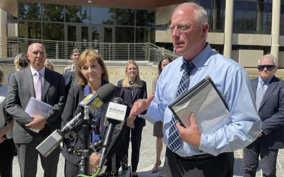 Lorenz standing, holding legal pad and talking into microphone.