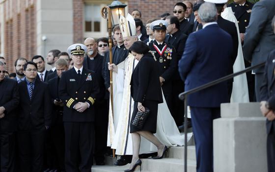 Gayle Benson, widow of NFL New Orleans Saints and NBA New Orleans Pelicans owner Tom Benson, walks down the steps to receive his casket with New Orleans Archbishop Gregory Aymond for visitation at Notre Dame Seminary in New Orleans on March 21, 2018. (AP file photo/Gerald Herbert)
