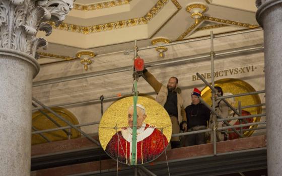 A man hangs a medallion from an elevated balcony.