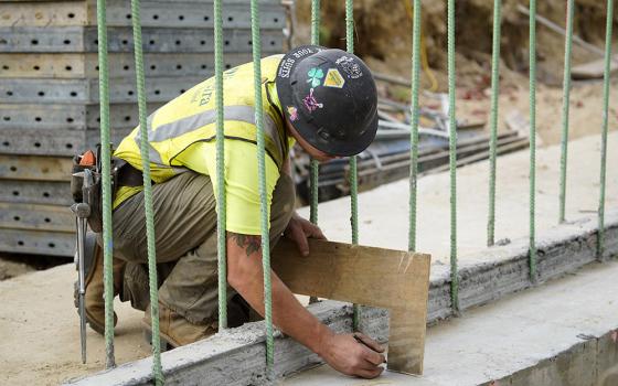 A worker takes a measurement at a highway construction site in Stony Brook, N.Y., Aug. 30, 2022. (CNS/Gregory A. Shemitz)