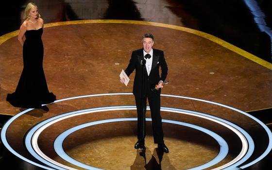 Peter Straughan accepts the award for Best Adapted Screenplay for "Conclave" during the Oscars on Sunday, March 2, 2025, at the Dolby Theatre in Los Angeles. Amy Poehler looks on from left. (AP/Chris Pizzello)