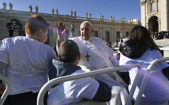 Pope Francis greets the crowd in St. Peter's Square at the Vatican while riding in the popemobile with a group of children before his general audience March 15, 2023. (CNS/Vatican Media)