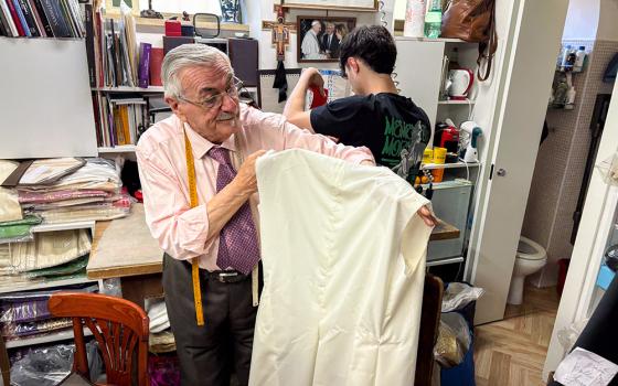 In his workshop in Rome by the Vatican, Raniero Mancinelli holds one of the three papal robes that he is preparing for the next pope to wear on the day of his election. (Camillo Barone)