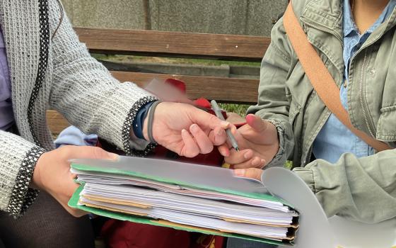 A client and her attorney, at left, go over paperwork at the George H. Fallon Federal Building in Baltimore, a check-in field office for the U.S. Immigrations and Customs Enforcement. Documents have been obscured for privacy. (NCR photo/Patricia Zapor)