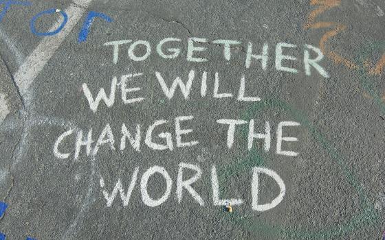 A phrase written in chalk on pavement says "Together we will change the world" (Unsplash/Priscilla Gyamfi)
