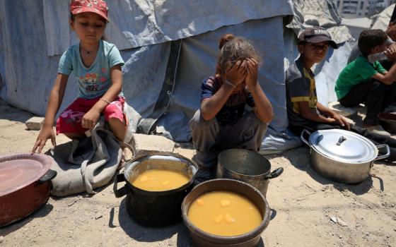 Palestinian children react near pots of food from a charity kitchen in Gaza City July 25, 2025, amid a hunger crisis. For months, U.N. officials, aid groups and experts have warned that Palestinians in the Gaza Strip are on the brink of famine without formally declaring one. (OSV News/Dawoud Abu Alkas/Reuters)