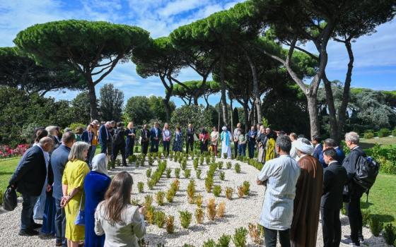 Participants in the multifaith dialogue of the Global Ethical Stocktake stand together in prayer in the Borgo Laudato Si', Italy Oct. 1. A group of 35 Catholics, religious leaders, Indigenous, environmental activists and academics participated. (Laudato Si' Movement/José Javier Garcia Cabrera)