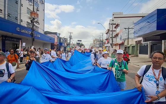 Catholics with the Laudato Si' Movement carry the "River of Hope" banner through the streets of Belém, Brazil, at the global climate march Nov. 15 during the COP30 United Nations climate change conference. (Eduardo Campos Lima)