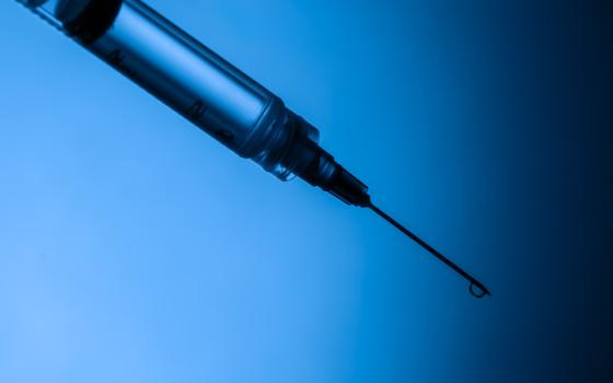 A syringe with a sharp, dripping needle tip against a gradient blue-to-black background