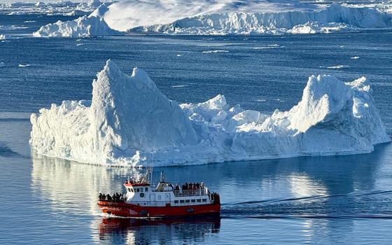 A boat navigates around a portion of an iceberg near Nuuk, Greenland, in this undated photo provided by Fr. Tomaž Majcen, a Conventual Franciscan, and the only Catholic parish priest serving in Greenland. Majcen says talks about a U.S. takeover are being met with concern, fear and "a quiet strength" by residents. (OSV News/Fr. Tomaž Majcen)