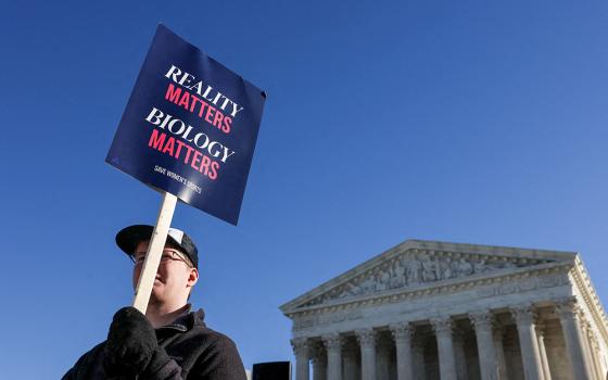 A supporter of keeping female sports based on biological sex holds a placard outside the U.S. Supreme Court in Washington Jan. 13, 2026, on the day justices heard oral arguments in two cases concerning efforts to enforce state laws banning transgender athletes from female sports teams at public schools. (OSV News/Reuters/Tyrone Siu)