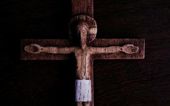 A weathered wooden crucifix against a dark background (Unsplash/Rui Silva, SJ)
