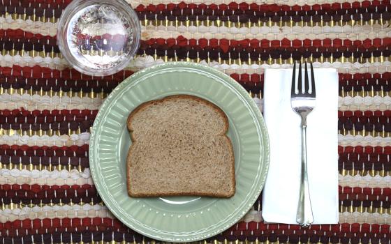 A slice of bread and glass of water are pictured in an illustration. "When I was in formation, I was taught to fast, especially from the things I love most at both the personal and community levels," writes Sr. Alice Nyazungu. (OSV News/Bob Roller)