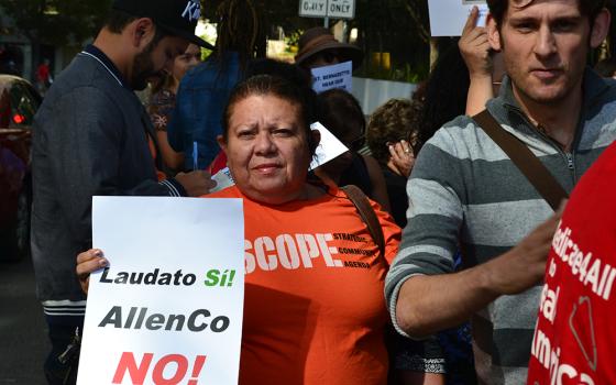 A community activist holds a sign referencing Pope Francis' encyclical Laudato Si' during a rally Oct. 4, 2017 outside the chancery of the Los Angeles Archdiocese. Residents and allies of the University Park neighborhood were urging the archdiocese to end its lease with AllenCo Energy at the oil drilling site linked to health issues in their community. (Courtesy of STAND-LA)