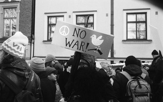 Person holding a sign that says, "NO WAR!" (Unsplash/ench)