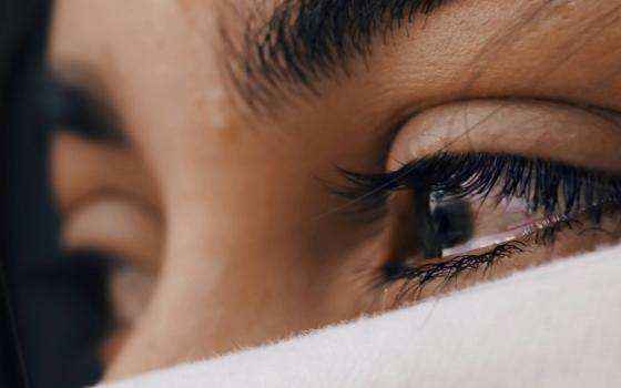 A close-up shows a woman's eyes, which are tearing up. (Unsplash/Louis Galvez)