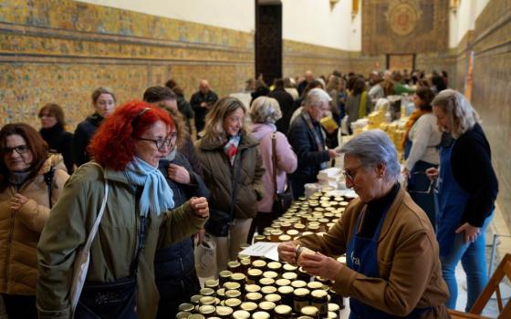 Customers buy marmalades and cakes made by cloistered nuns, at a market at the Reales Alcazares in Seville, Spain, on Dec. 5, 2023. Women's religious communities in Spain are making and selling items, and renting rooms in their monasteries, to generate income. (AP/Laura Leon)
