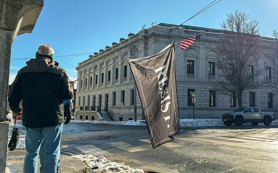 A protester holds a "Resist" flag in front of federal court in Portland, Maine, as Immigration and Customs Enforcement conduct operations in the state, Jan. 22, 2026. (AP/Rodrique Ngowi)
