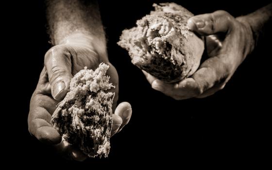 Hands offer a piece of broken bread (Dreamstime/Shaiith)