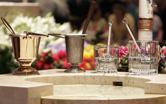 Aspersoriums with aspergillums used for sprinkling holy water are seen near a baptismal font during Easter Mass at a church in New York, in this file photo. (OSV News/Gregory A. Shemitz)