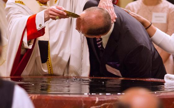 A file photo shows a catechumen being baptized during the Easter Vigil. (OSV News/Texas Catholic Herald/James Ramos)