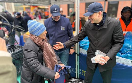 Archbishop Ronald Hicks of New York, right, and CEO of Catholic Charities New York Antonio Fernandez help volunteers distribute food to residents of Washington Heights in Northern Manhattan, on Holy Thursday, April 2. (NCR photo/Camillo Barone)