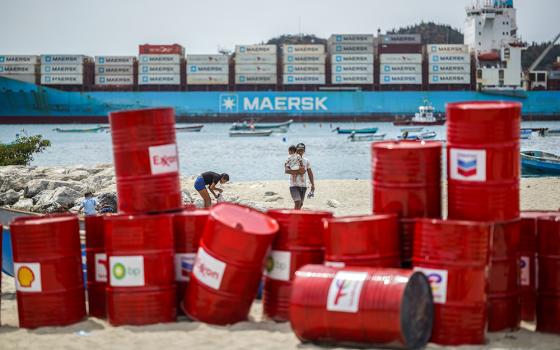A family walks near a Make Polluters Pay demonstration along the Caribbean Sea April 27, 2026, in Santa Marta, Colombia. Protesters were demanding oil companies pay for the energy transition during a nearby conference aimed at transitioning away from fossil fuels. (AP/Ivan Valencia)