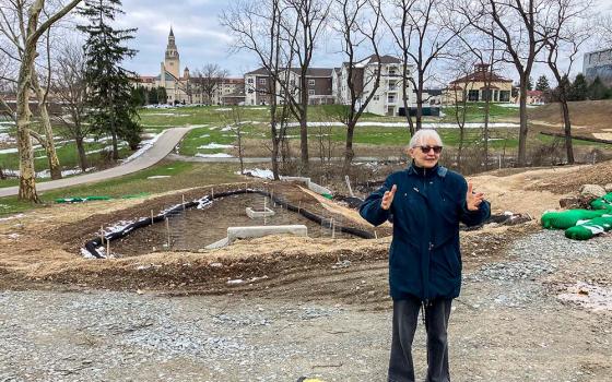 Stefani Danes stands on the Rachel Carson EcoVillage's construction site. The building with a high tower in the background is the Sisters of Divine Providence's 100-year-old convent, now part of La Roche University. (Jennifer Szweda Jordan)