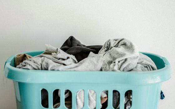 A blue laundry basket filled with clothes (Unsplash/Annie Spratt)