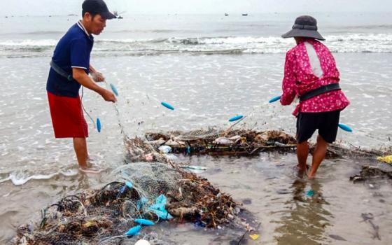 Workers remove trash from a clam-farming area in Vinh An, Vietnam, on June 17, 2026. Farmers say plastic waste and other flood-borne debris have contributed to declining harvests. (Joachim Pham)