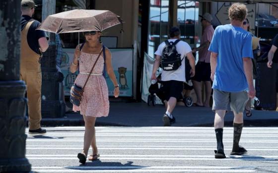 A person uses an umbrella for shade from the sun while walking near Pike Place Market June 29, 2021, in Seattle. The unprecedented heat dome that summer baked the Pacific Northwest for weeks in record-breaking extreme heat. More than 650 people died across the U.S. and Canada, including at least 19 in Spokane. (AP/Ted S. Warren)