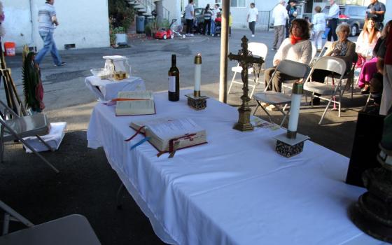 Neighborhood residents gather before an altar set up in a carport at a low-rise apartment complex for a "Misa Del Barrio," or "Neighborhood Mass," in Campbell, California, Aug. 21, 2026. A statue of Our Lady of Guadalupe stands behind the altar. (Marissa Nichols)