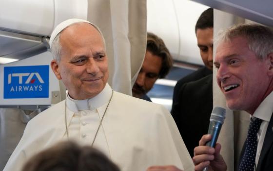 Pope Leo XIV looks on as Matteo Bruni, head of the Vatican press hall, speaks to journalists aboard the papal flight from Rome to Paris Sept. 25, 2026, at the start of his apostolic journey to France and visit to UNESCO. (CNS/Lola Gomez)