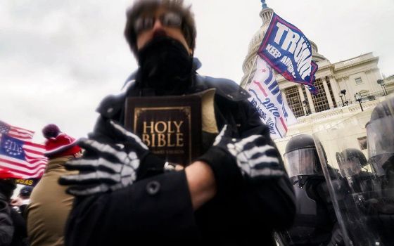 In this Jan. 6, 2021, file photo, a man holds a Bible as Trump supporters gather outside the Capitol in Washington. (RNS/AP/John Minchillo)