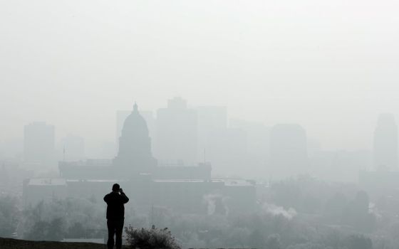 A man stops to take a picture of the Utah State Capitol and buildings that are shrouded in smog in downtown Salt Lake City Dec. 12, 2017. (CNS/Reuters/George Frey)