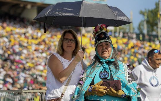 Two women listen as Pope Francis celebrates Mass at Commonwealth Stadium, July 26 in Edmonton, Alberta. Francis traveled to Canada to apologize to Indigenous peoples for the abuses committed by Catholic missionaries in the country’s residential schools. 