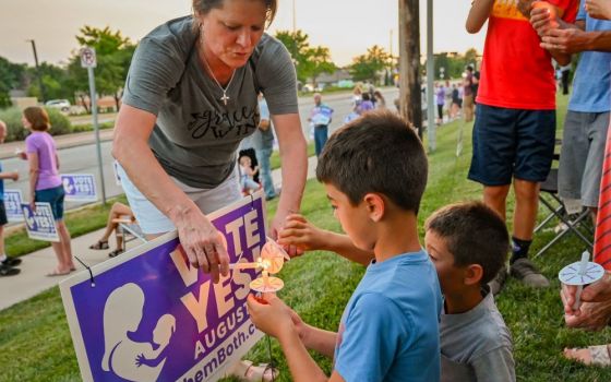 A woman helps two young boys light candles during a "Value Them Both" sidewalk vigil in Olathe, Kansas, Aug. 1. 
