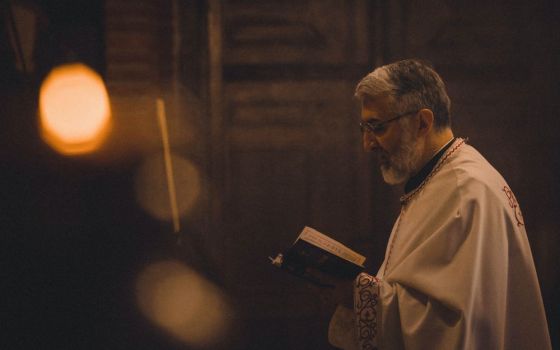 Picture of a priest holding a book (Unsplash/Tamara Govedarov)