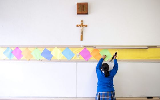 A student staples colored paper to the wall of a classroom after summer school July 18, 2012, at Our Lady of Lourdes in Los Angeles. (AP/Grant Hindsley)