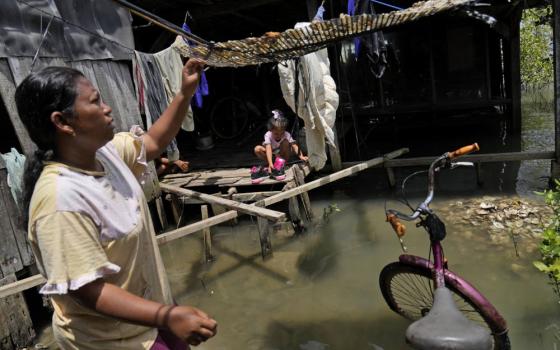 Nia Riningsih, one of the few residents who stayed behind after rising sea levels inundated their neighborhood on the northern coast of Java Island, checks salted fish she dries at their house in Mondoliko village, Central Java, Indonesia, Nov. 7, 2021.