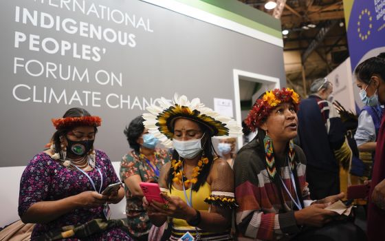 Members of the International Indigenous People's Forum on Climate Change look at their phones Nov. 3 at the COP26 U.N. Climate Summit, in Glasgow, Scotland. (AP photo/Alberto Pezzali)