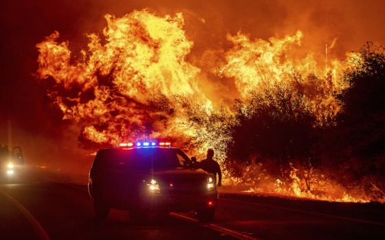 Flames lick above vehicles on Highway 162 as the Bear Fire burns in Oroville, California, on Sept. 9, 2020. The blaze, part of the lightning-sparked North Complex, expanded rapidly as winds buffeted the region. (AP Photo/Noah Berger)