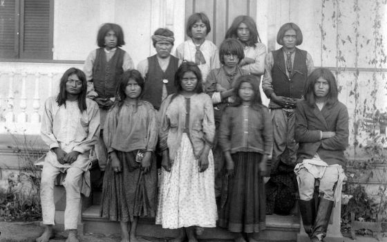 Native American (Chiricahua Apache) boys and girls pose outdoors at the Carlisle Indian Industrial School in Carlisle, Pennsylvania, after their arrival from Fort Marion, Florida, in November 1886. Photo by J. N. Choate/Creative Commons