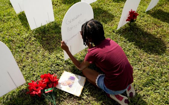 Kyla Harris, 10, writes a tribute Nov. 24 to her grandmother Patsy Gilreath Moore, who died at age 79 of COVID-19, at a symbolic cemetery created to remember and honor lives lost to COVID-19 in the Liberty City neighborhood of Miami. (AP/Lynne Sladky)