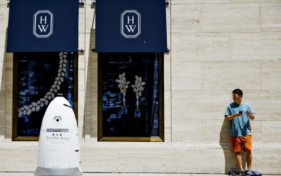 A new security robot drives toward Daniel Webb as it patrols the sidewalks and parking garage of the River Oaks District shopping complex Aug. 18 in Houston. (AP/Houston Chronicle/Michael Ciaglo)