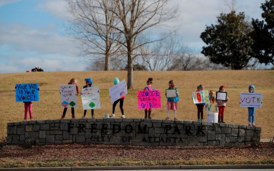 Girl Scouts in Atlanta hold signs urging residents to vote in the runoff election for both of Georgia's U.S. Senate seats Jan. 3, 2021. (CNS/Reuters/Brian Snyder)