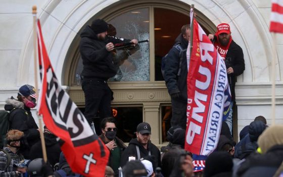People carry flags with words "Jesus" and "Trump" on them as a President Donald Trump supporter breaks a window at the U.S. Capitol in Washington Jan. 6, 2021. (CNS photo/Leah Millis, Reuters)