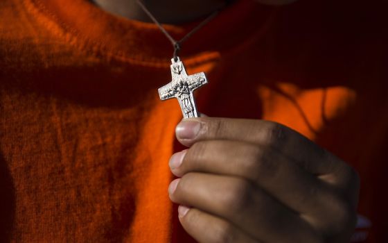 A young man holds a crucifix as he and other immigrants attend Mass on the U.S. side of the border in El Paso, Texas, Feb. 17, 2016. (CNS/Nancy Wiechec)